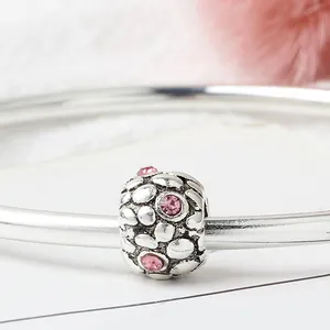 Macro shot of silver charm bead featuring pink zircon stones on a polished bracelet