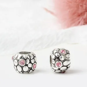 Vintage silver hollow charms with pink rhinestones for DIY bracelets on white surface