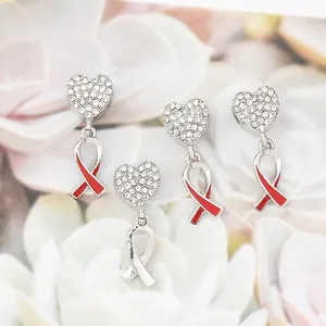 Macro view of heart-shaped diamond earrings with red awareness ribbon pendants