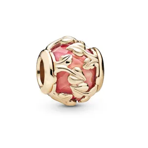 Macro detail of rose gold vine charm with faceted pink crystal and ALE MET engraving