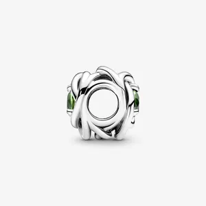 Macro view of silver woven hollow charm with green crystal accents for jewelry making