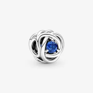 Detailed view of woven silver charm featuring a faceted round deep blue gemstone inlay