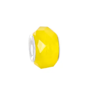 Vue macro d'une perle en acrylique facettée jaune vif avec un insert central en métal argent