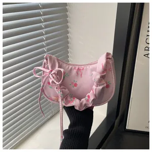Detailed close-up of pink floral handbag featuring ruffled strap and bow drawstring detail