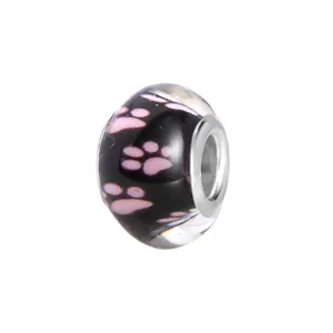 Macro detail van zwarte glazen kraal met roze pootafdrukken en metalen kern voor DIY-armbanden