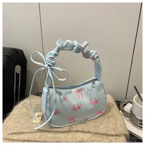 Close-up of floral drawstring handbag with pink roses and ruffled handle on felt mat