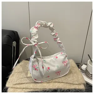 Detail of floral handbag featuring pink roses and pleated handle on a cozy knit background