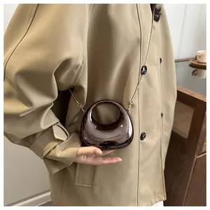 Close-up of a mini dark brown glossy handbag with hollow handle and gold chain strap