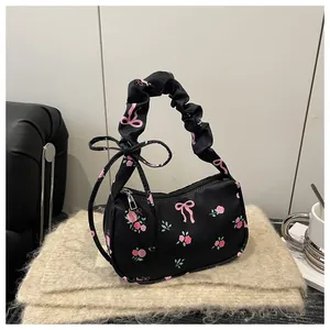 Detail of floral handbag featuring ruched handles, pink rose print, and side bow accents