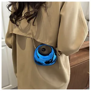 Detail of electric blue metallic mini bag with a round cutout and gold chain on a trench coat