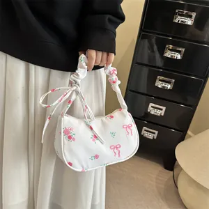Floral print shoulder bag with pink bow accents and pleated handle shown on model