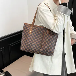 Klassieke grote geruite tote bag met bruine lederen riemen gedragen door een model