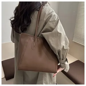Détail d'un grand sac cabas en similicuir marron foncé porté à l'épaule par un mannequin