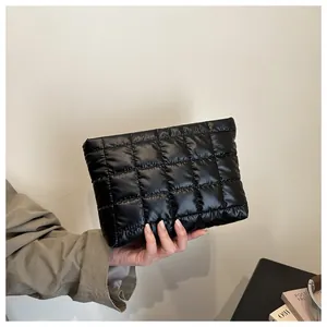 Détail d'une pochette matelassée noire montrant la texture bouffante et le tissu nylon