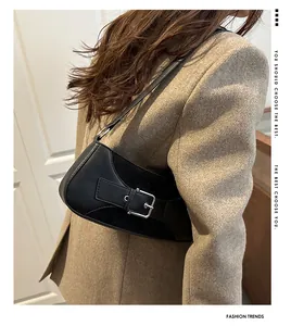 Detailopname van de zwarte vintage schoudertas met metalen gesp op wollen blazer
