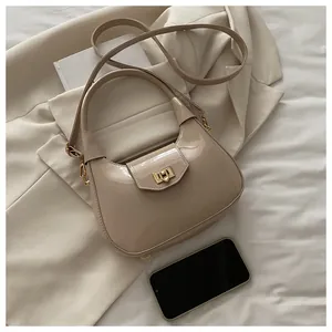 Detailansicht der beigen glänzenden Lacklederhandtasche mit goldenem Metalldrehverschluss
