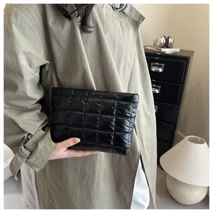 Close-up of black quilted puffer cosmetic bag held by a model in a trendy outfit