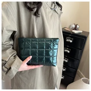 Deep green quilted nylon pouch held by model in a stylish trench coat setup