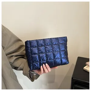 Gros plan d'un mannequin tenant la pochette matelassée bleu marine au tissu brillant
