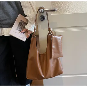 Detail of caramel brown hobo bag with matching small zippered pouch on a door handle