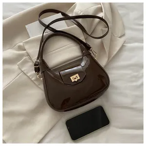 Details einer dunkelbraunen Lackleder-Hobo-Tasche mit goldenem Drehverschluss und Glanz