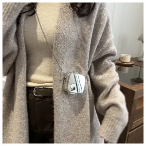 Détail du mini sac bandoulière argenté miroir en acrylique porté sur un cardigan