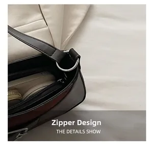 Detailopname van een donkerbruine baguette-tas met zilveren rits en binnenzak