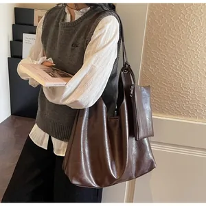 Detail of a large brown soft leather tote bag with a matching mini pouch and pleated design