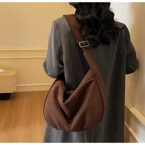 Détail du sac hobo en cuir dépoli marron foncé avec boucle argentée réglable sur la bandoulière