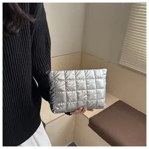 Detail of silver metallic quilted clutch bag with zipper showing material and hand-held size