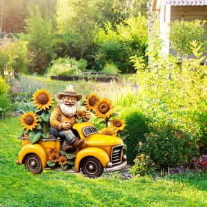 Garden gnome in a yellow vintage truck planter with sunflowers on green lawn detail