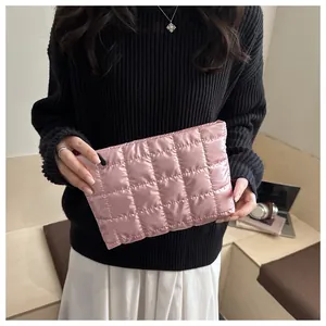 Détail de la pochette matelassée en satin rose clair avec fermeture éclair et texture douce