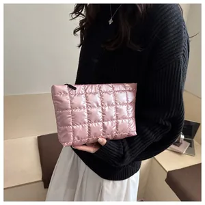 Détail d'une trousse à maquillage rose en tissu matelassé tenue à la main à carreaux