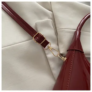 Detail der weinroten Lackledertasche mit hochwertigen goldenen Metallschnallen