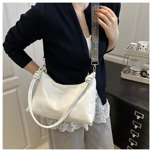 Detail of white moon bag with woven spiral handle and colorful ethnic style strap