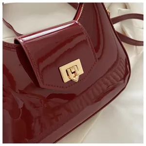 Detailansicht der weinroten Lacklederhandtasche mit goldenem Drehverschluss-Design
