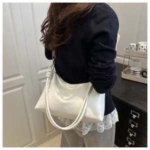 Detail view of white leather shoulder bag with decorative knotted strap and smooth texture