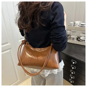 Detail view of glossy brown vintage hobo bag with dual thin straps and knot decoration