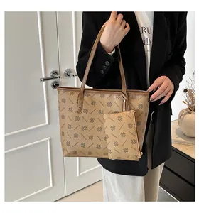 Detailed view of brown tote bag with clover monogram and matching small pouch accessory