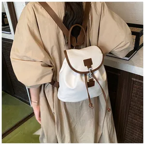 Detail of cream and brown backpack featuring adjustable straps and polished metal buckle closure