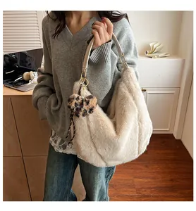 Detail of beige faux fur hobo bag featuring leopard heart charm and chain link handle