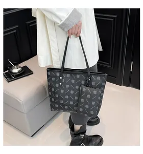 Detail of a black monogram tote bag with a small matching pouch charm for daily commute