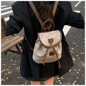Detail of grey canvas backpack with brown leather trim and metal clasp on model
