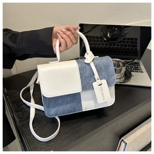 Sac à main bicolore en denim et cuir blanc avec poignée et breloque étiquette mode