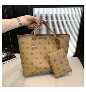 Detail of khaki tote bag set with clover pattern and brown handles held by a person