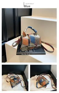 Detail of blue color-block square bag with lychee grain texture and leather handle