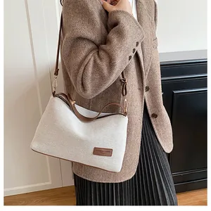 Detail of linen and brown leather patchwork shoulder bag with FASHION & BAGS logo label
