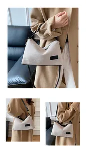 Detail of linen canvas tote with black leather trim and embossed brand tag on surface