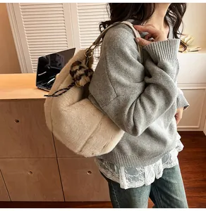 Detail of plush beige tote bag with leopard print pom charm and leather shoulder strap