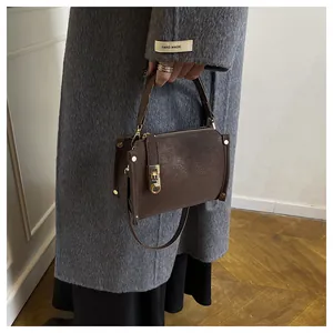Detail showing the brown lychee pattern leather handbag with gold metal lock and shoulder strap